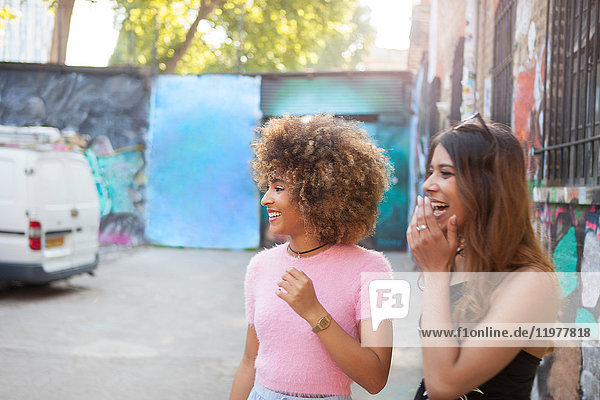 Two young women in street  looking away  laughing