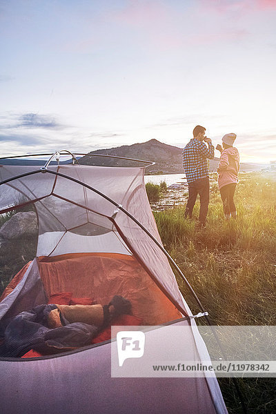 Paar steht in der Nähe des Zeltes  trinkt heiße Getränke und schaut auf die Aussicht  Heeney  Colorado  Vereinigte Staaten