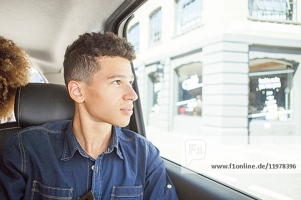 Young man in passenger seat of car  looking out of window