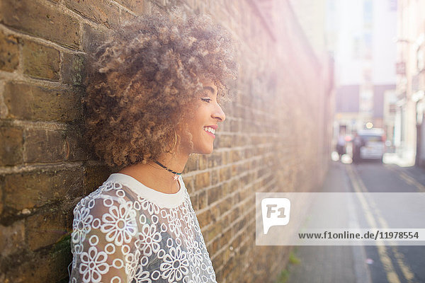 Young woman leaning against wall  smiling