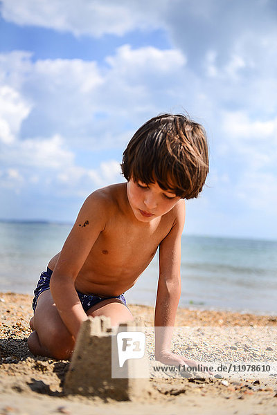 Junge macht Sandburg am Strand