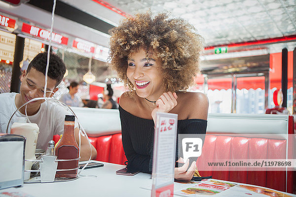 Friends sitting in diner  young woman looking away  smiling