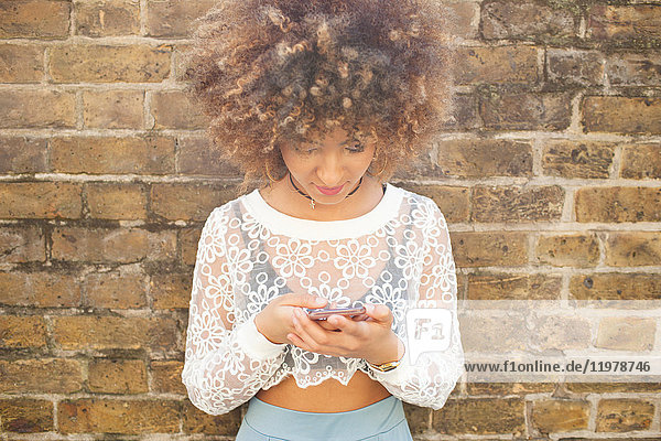 Young woman leaning against wall  using smartphone