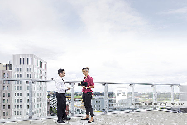 Geschäftsmann und Frau unterhalten sich auf dem Dach