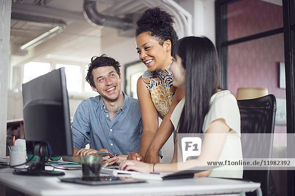 Coworkers smiling in front of computer monitor