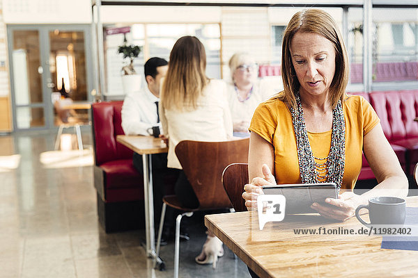 Woman using digital tablet in cafeteria