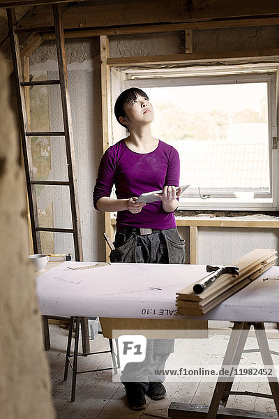Woman working on renovating old attic with tablet
