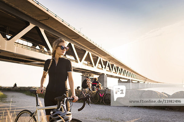 Woman with bicycle, two friends in background