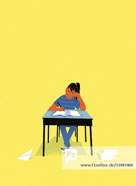 Bored schoolgirl sitting writing at school desk