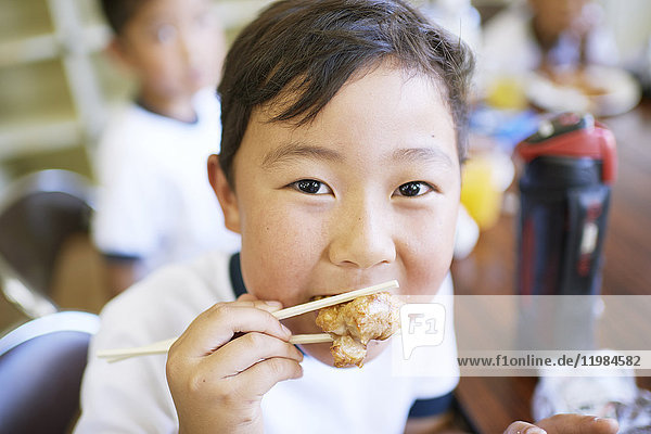 Japanisches Grundschulkind beim Essen im Klassenzimmer