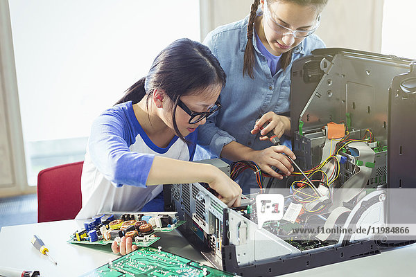 Girl students assembling computer in classroom