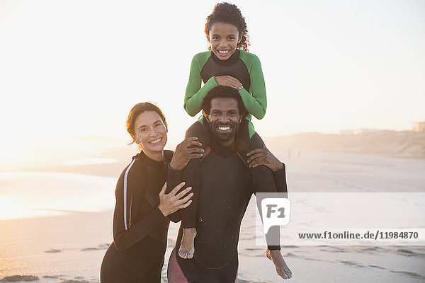 Portrait smiling  happy family in wet suits on sunny summer beach