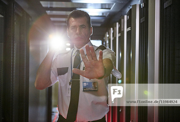Portrait male security guard with flashlight gesturing stop in server room