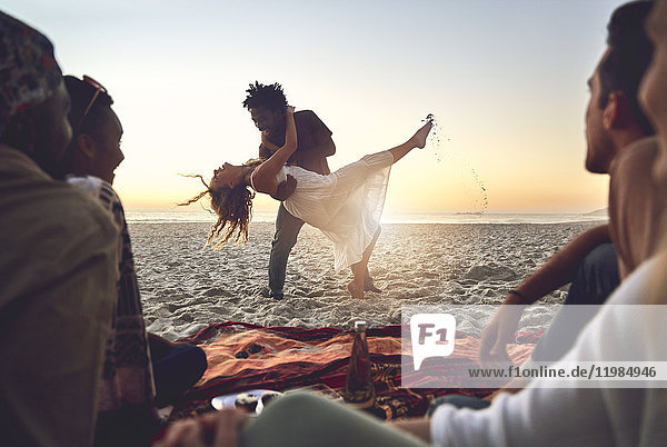 Playful young couple dancing on sunny summer beach
