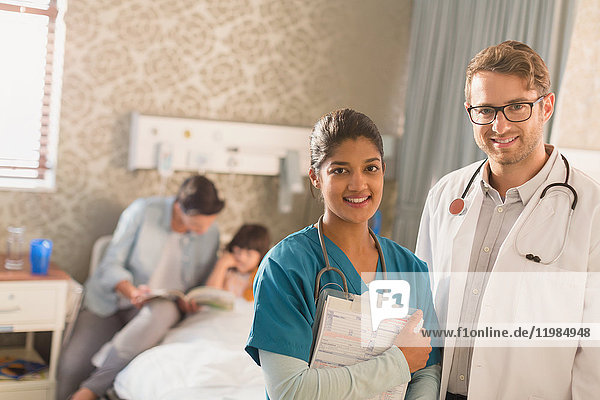 Porträt eines lächelnden  selbstbewussten Arztes und einer Krankenschwester bei der Visite in einem Krankenhauszimmer