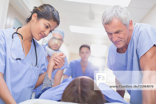 Pflegende Chirurgen im Gespräch mit einem Patienten auf einer Bahre im Krankenhausflur