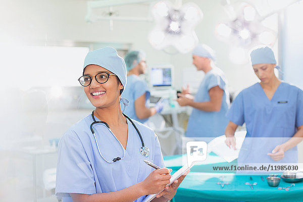 Lächelnde Chirurgin mit Klemmbrett im Operationssaal