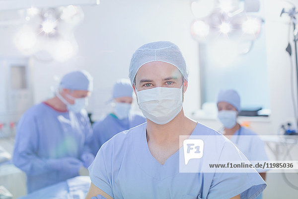 Porträt eines selbstbewussten jungen Chirurgen mit chirurgischer Maske im Operationssaal