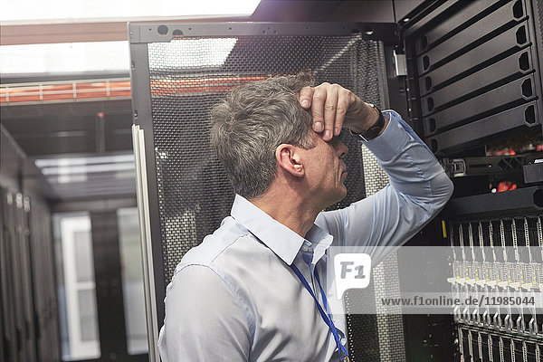 Frustrated IT technician at panel in server room