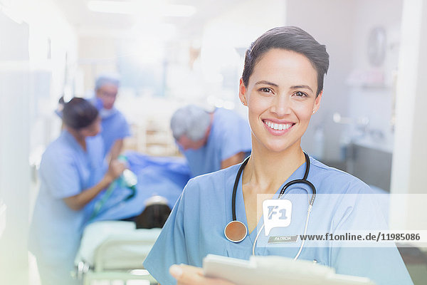 Portrait smiling  confident female surgeon with clipboard in hospital corridor
