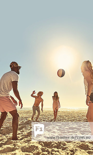 Young friends playing with beach ball on sunny summer beach