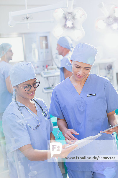 Weibliche Chirurgen  die im Operationssaal Papierkram am Klemmbrett überprüfen