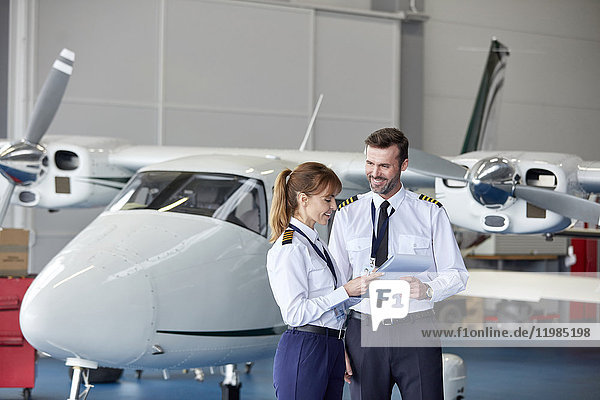 Piloten diskutieren Papierkram in der Nähe des Flugzeugs im Hangar