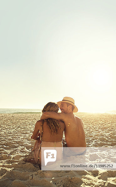 Affectionate young couple hugging on sunny summer beach