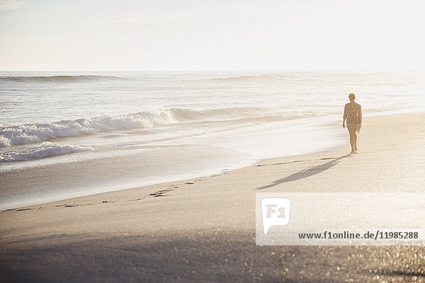 Silhouette woman walking on idyllic sunny summer beach