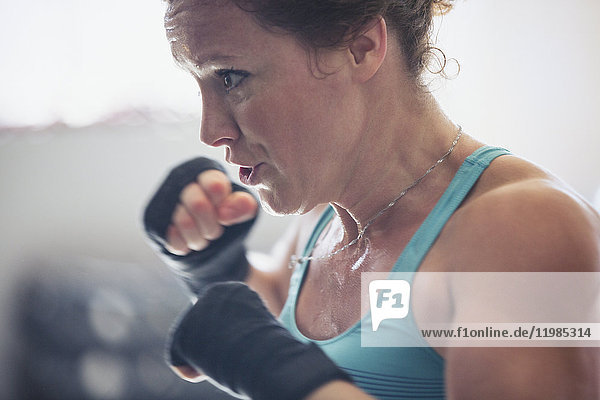 Close up determined  tough female boxer shadowboxing