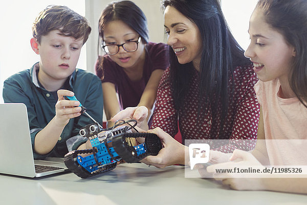 Lehrerin und Schülerinnen beim Programmieren und Montieren von Robotern im Unterricht