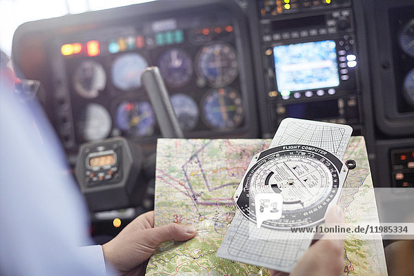 Pilot überprüft Navigationskarte und Kompassinstrument im Flugzeugcockpit