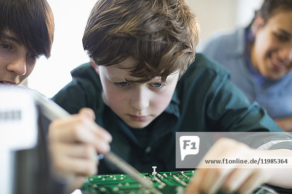 Fokussierter Schüler beim Zusammenbau von Elektronik im Klassenzimmer
