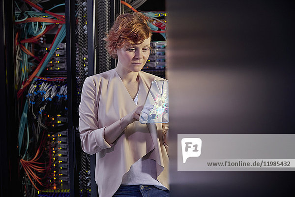 Female IT technician using futuristic digital tablet in server room