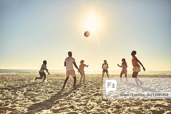 Junge Freunde spielen mit Beachball am sonnigen Sommerstrand