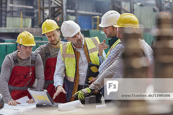 Vorarbeiter  Ingenieure und Arbeiter bei einem Laptop-Treffen  bei dem Pläne in der Fabrik besprochen werden.