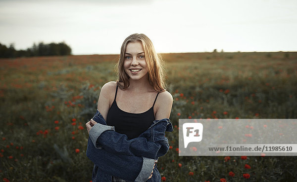 Portrait lächelnde junge Frau auf dem Land mit Wildblumen