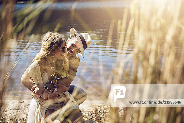 Zärtliches junges Paar,  das sich am sonnigen Sommerufer umarmt.