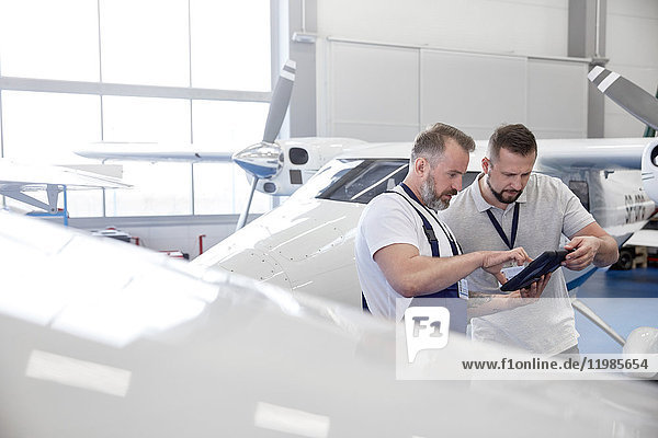 Mechaniker mit digitalem Tablett in der Nähe des Flugzeugs im Hangar