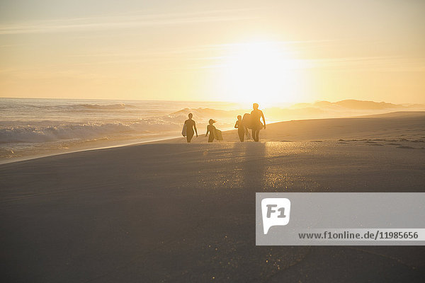 Silhouette family walking on sunny summer sunset beach