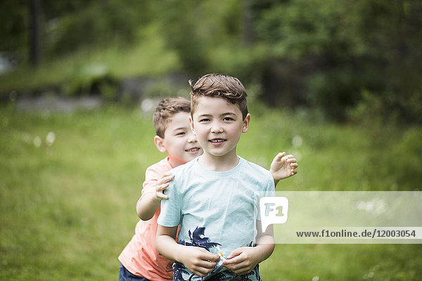 Portrait of boy with playful brother standing in back yard