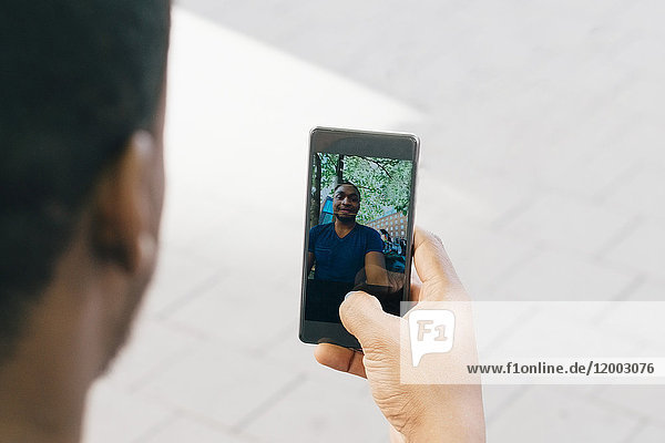 Abgeschnittenes Bild eines jungen Mannes  der Selfie vom Smartphone nimmt.