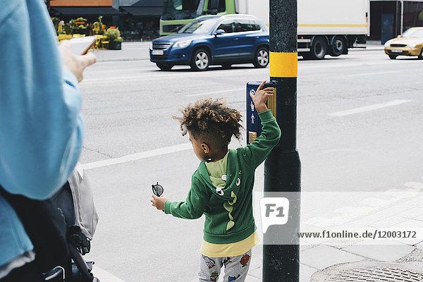 Rückansicht des Jungen mit Mutter auf dem Fußgängerübergangsschild in der Stadt