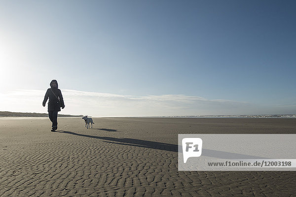 Germany  Lower Saxony  East Frisia  Langeoog  woman with dog on the beach