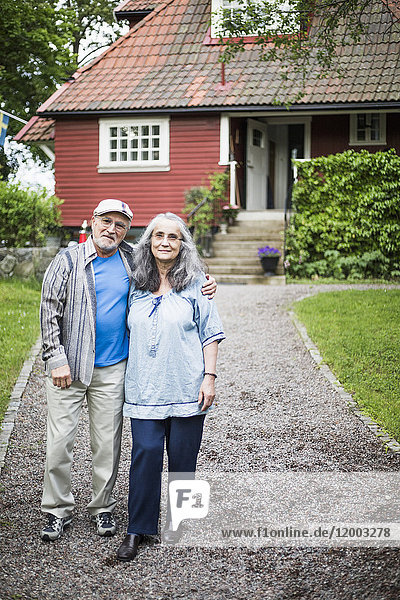 Porträt eines älteren Paares auf einem Fußweg gegen das Haus stehend