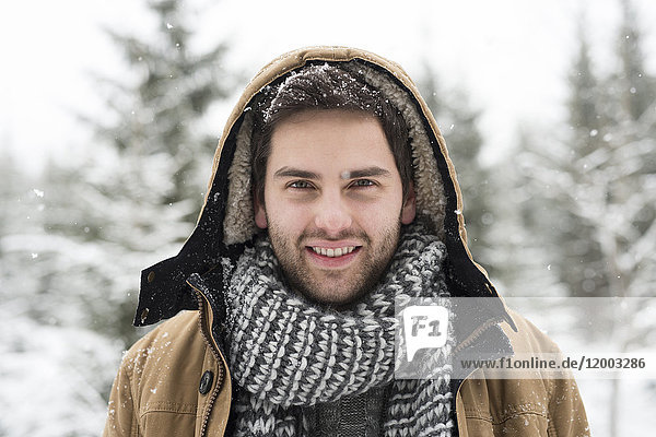 Porträt eines lächelnden jungen Mannes im Winter