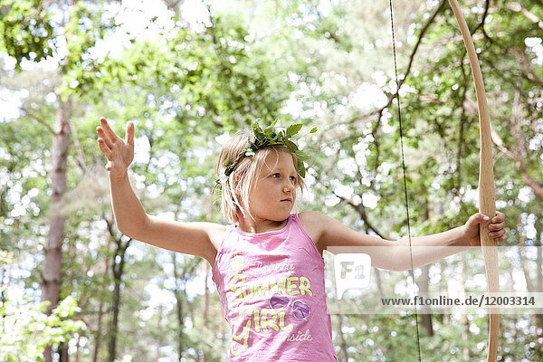 Mädchenschießen mit Pfeil und Bogen im Wald