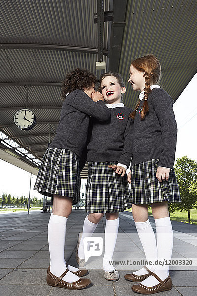Drei Mädchen auf dem Bahnsteig in Schuluniform