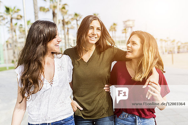Three happy female friends strolling on the boardwalk