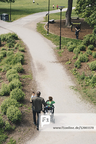 High angle view of man with children walking on pathway towards park